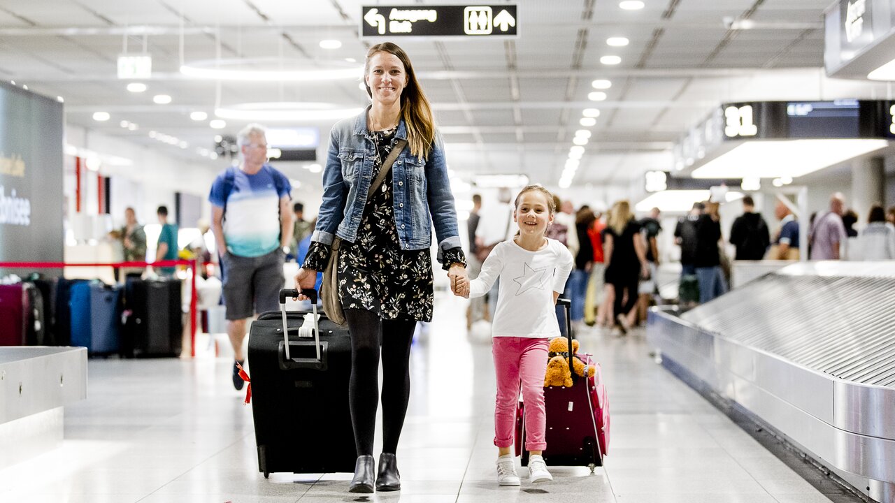 Mutter mit Kind und Rollkoffern im Gepäckbereich des Flughafens Stuttgart