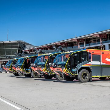 Reihe moderner Flughafenlöschfahrzeuge vor der Feuerwache des Flughafen Stuttgart bei sonnigem Wetter