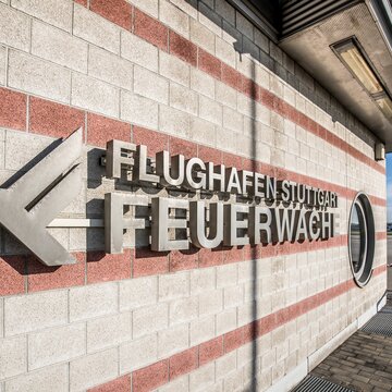 Fassadenansicht der Feuerwache am Flughafen Stuttgart mit moderner Beschriftung und Blick aufs Rollfeld