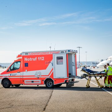 Rettungseinsatz mit Notarztwagen der Flughafenfeuerwehr Stuttgart am Vorfeld neben Flugzeug