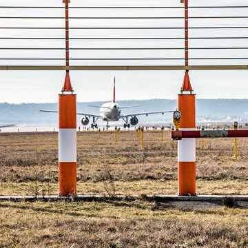 Flugzeug rollt auf der Landebahn des Flughafens Stuttgart, im Vordergrund Elemente des Anflug- und Navigationssystems.
