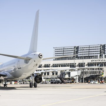 Flugzeug steht auf dem Vorfeld des Flughafens Stuttgart mit Blick auf das Terminalgebäude und angeschlossene Fluggastbrücken.