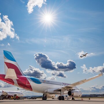 Flugzeuge auf dem Vorfeld des Flughafens Stuttgart bei Sonnenschein und blauem Himmel mit vereinzelten Wolken.