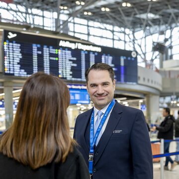 Flughafenmitarbeiter gibt Reisender am Flughafen Stuttgart Auskunft. 