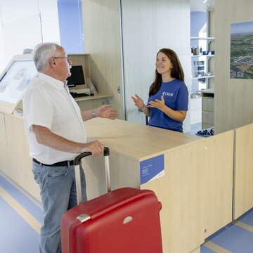 Reisender erhält Informationen an einem Informationsschalter im Flughafen Stuttgart.