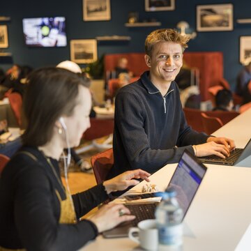 Personen arbeiten an Laptops in einer Lounge am Flughafen Stuttgart.